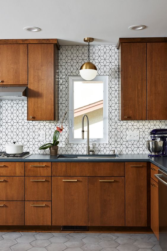a cozy, richly stained kitchen with graphite gray stone countertops and white geometric tiles on the back wall