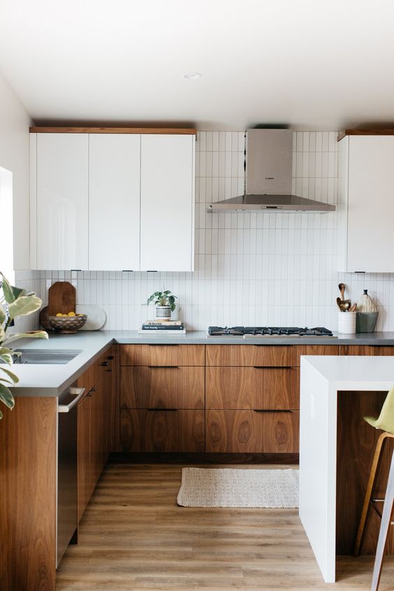 A chic mid-century modern kitchen with two-tone cabinets, gray stone countertops, a white thin tile backsplash, and neutral fixtures