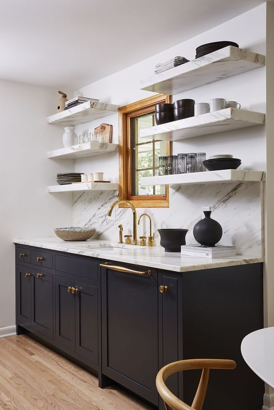 A sophisticated mid-century modern kitchen with dark gray cabinets, white stone open shelving, a backsplash and countertops