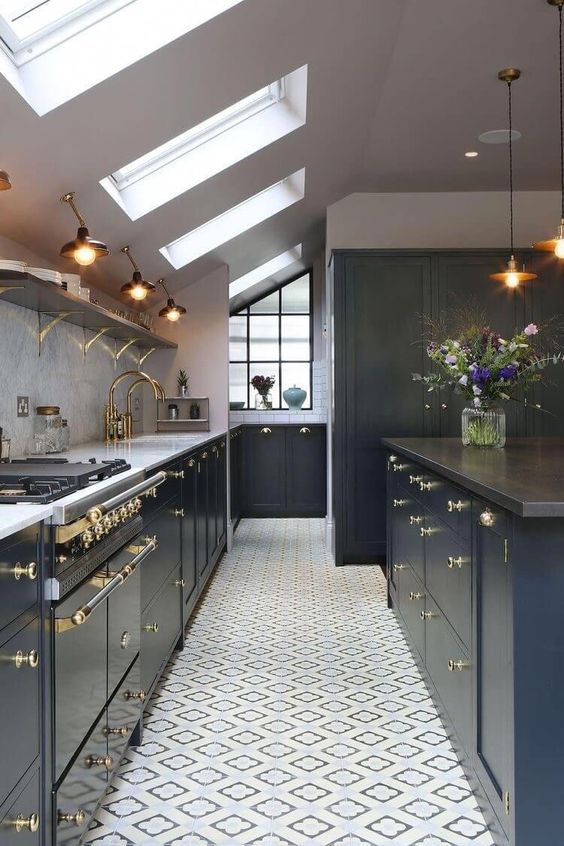 a navy blue attic kitchen with elegant gold accents, sconces and pendant lamps and lots of skylights to bring in more light