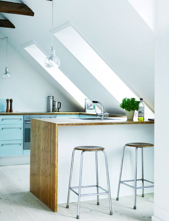 a Nordic loft kitchen with blue cabinets, a white island, butcher block countertops, and cool stools