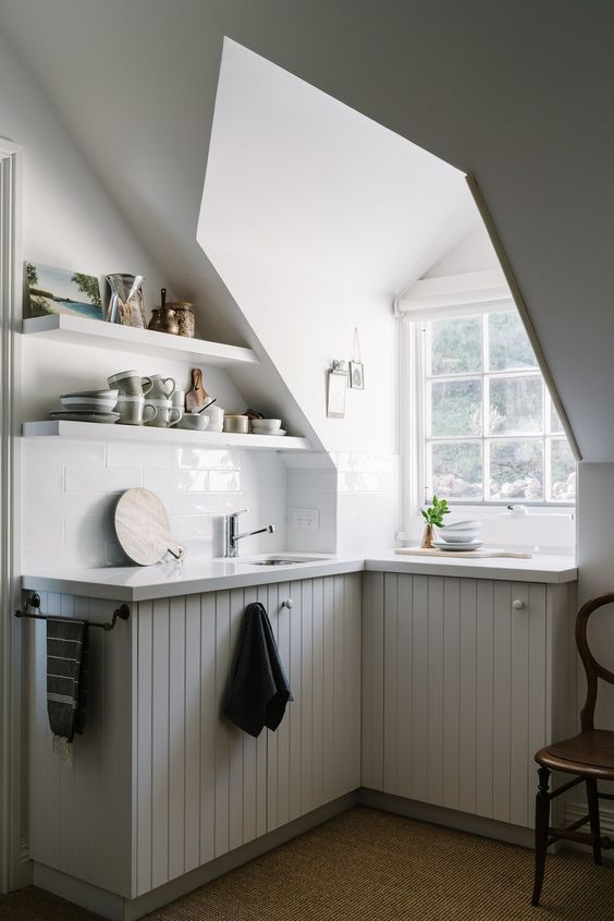 A small attic kitchen with a window, planked cabinets, open shelves and a vintage chair is a lovely idea to rock