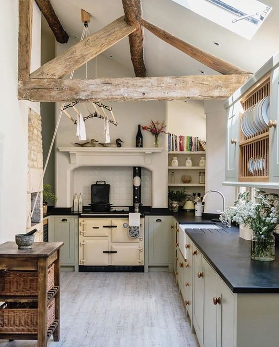 a vintage attic kitchen with gray cabinets, a stove, wooden beams, a wooden console table and some open storage spaces
