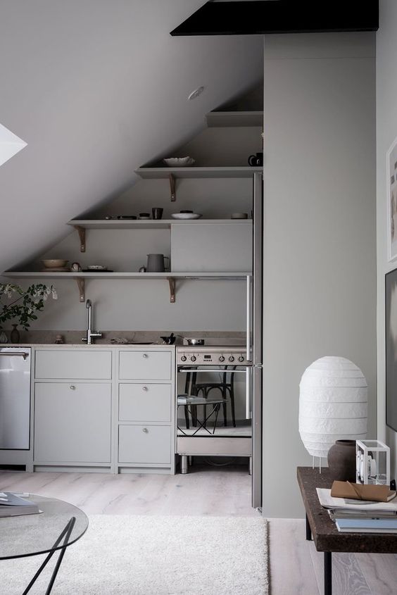 a minimalist kitchen in the attic with gray walls and cabinets, open shelving and stone countertops and some tables