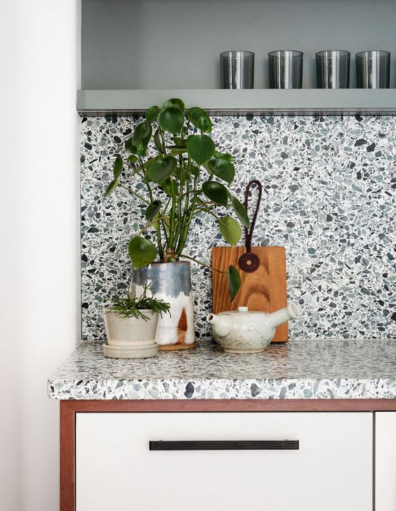 A chic modern kitchen in white with a bold and eye-catching terrazzo splashback and worktop and matching floating shelf