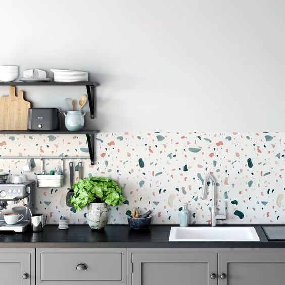 A gray kitchen with black countertops and a cheerful terrazzo backsplash and black metal shelves is a cool idea