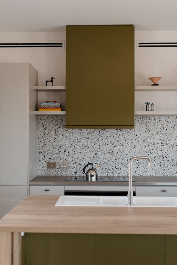 A minimalist gray and grass green kitchen with gray countertops and a cool black and white terrazzo backsplash