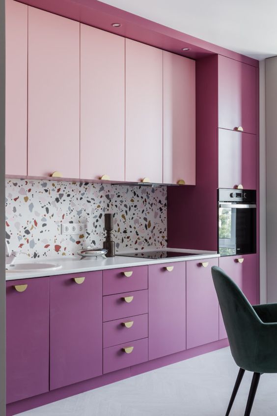 a purple-pink kitchen with gold knobs and a light terrazzo backsplash, plus white countertops for balance