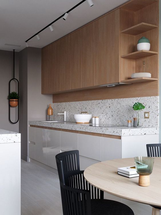 A white and stained kitchen is made more attractive with a white terrazzo backsplash and countertops and the same countertops on the kitchen island