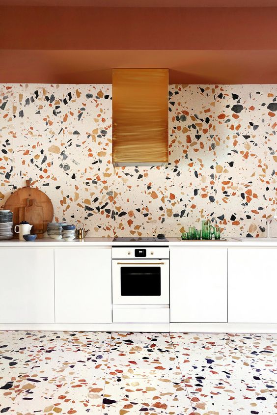 A white kitchen that is an eye-catcher with a terracotta-colored ceiling, a light terrazzo backsplash and a matching floor