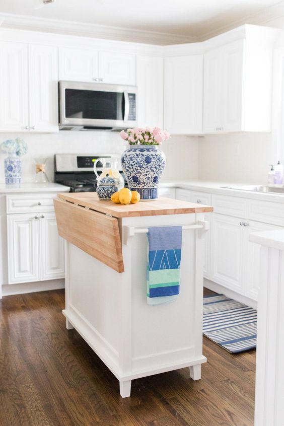 a crisp white kitchen with shaker-style cabinets and a matching small island with butcher block countertop for a coastal home