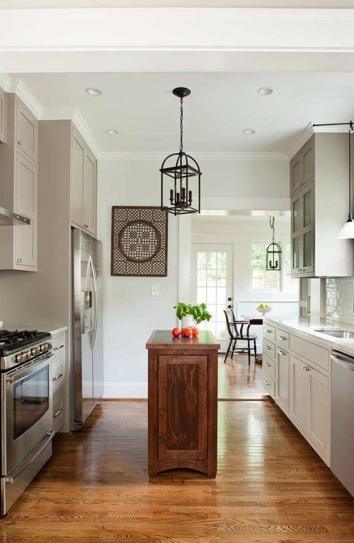 a dove gray country-style kitchen with white countertops and a richly stained wooden island that contrasts with the space