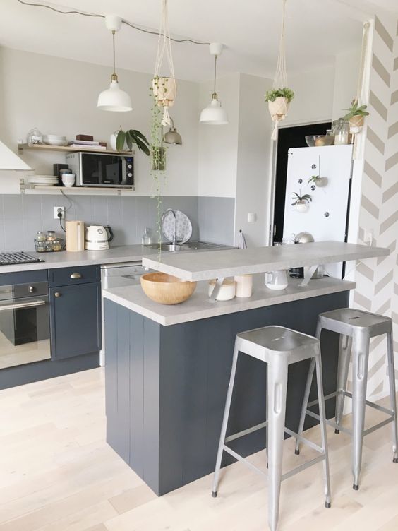 a graphite gray kitchen with a gray tile backsplash and a matching gray kitchen island with a raised worktop