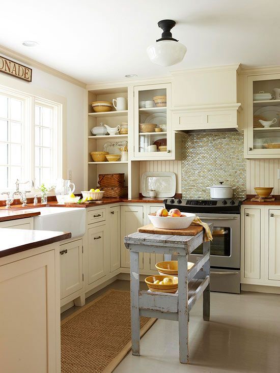 a neutral, warm-colored kitchen with green tiles, butcher block countertops, and a blue shabby-chic island