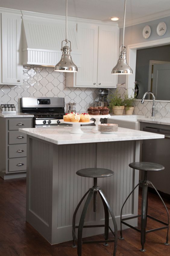 The original wraparound countertop was replaced with a space-saving kitchen island and breakfast bar with modern bar stools. All new appliances, an attractive range hood, marble countertops and pendant lighting were installed, and the tile backsplash adds a unique feel as seen on HGTV's Fixer Upper. (Detail)