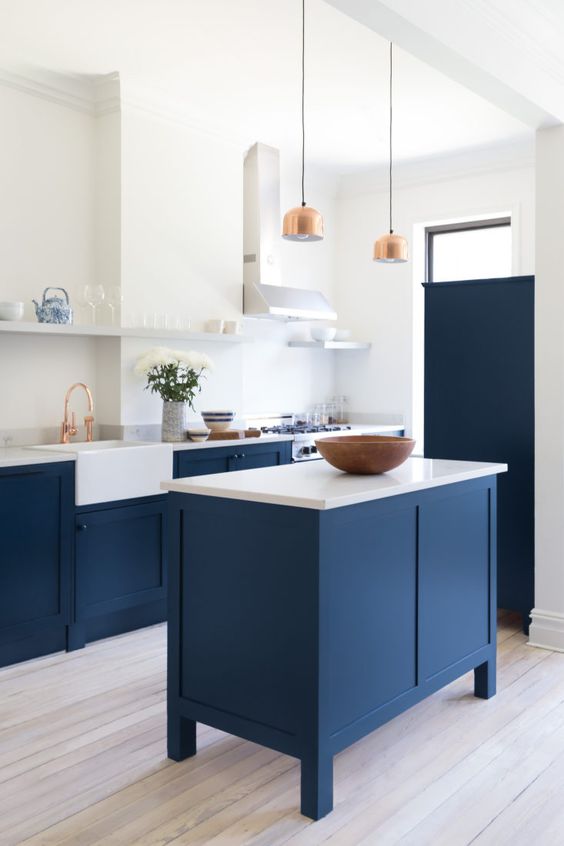 a super stylish modern kitchen in navy blue and white with copper accents and a small kitchen island that matches the cabinets