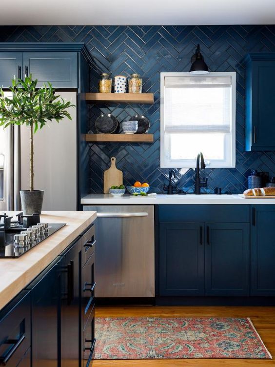 a modern blue kitchen with white quartz countertops, a matching blue herringbone backsplash and a touch of black here and there