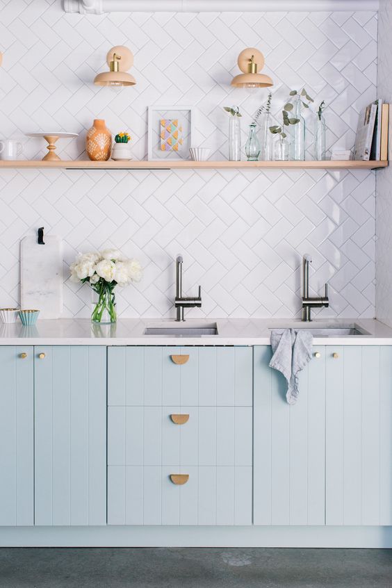 A light blue IKEA kitchen with white countertops and a white herringbone backsplash and floating shelves is fantastic