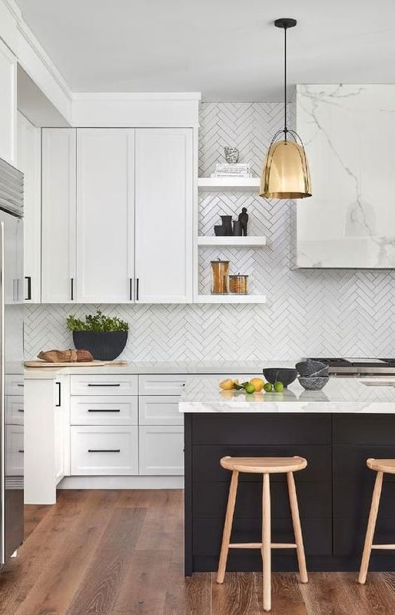a sophisticated, modern kitchen with white cabinets and a black island, white quartz countertops and a white herringbone backsplash