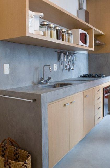 A light stained kitchen with a backsplash and concrete countertops and stainless steel handles is a laconic and cool idea