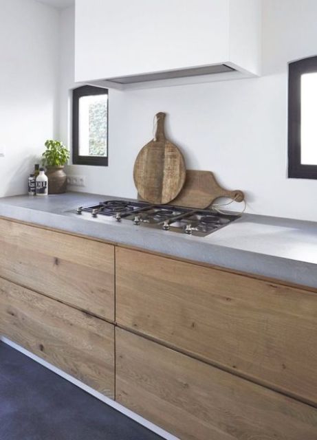 A minimalist, light-stained kitchen with a concrete countertop and a sleek white hood is a chic space that inspires