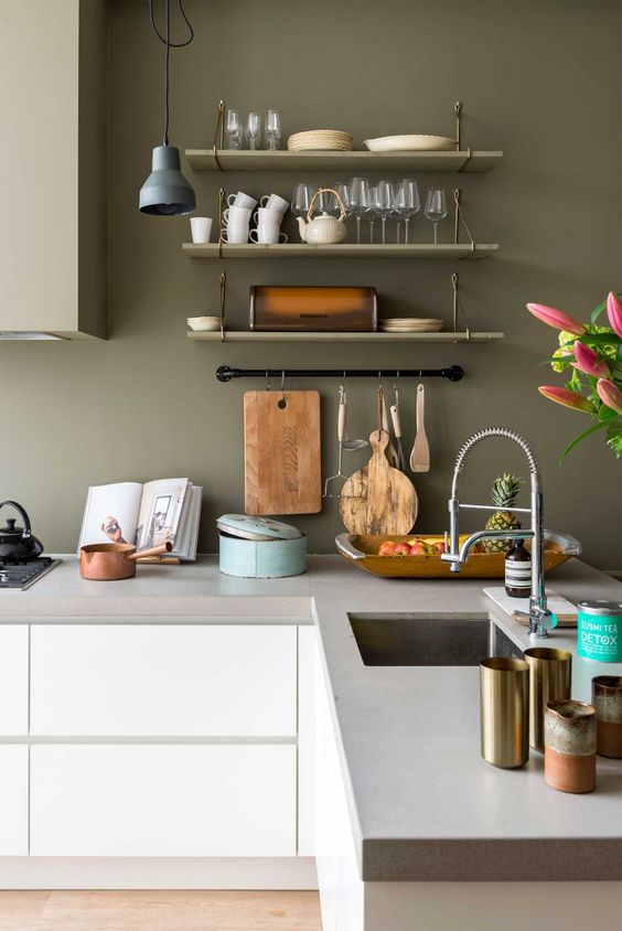 A calm Nordic kitchen with sleek white cabinets, concrete countertops, olive walls, and upper cabinets is a chic space