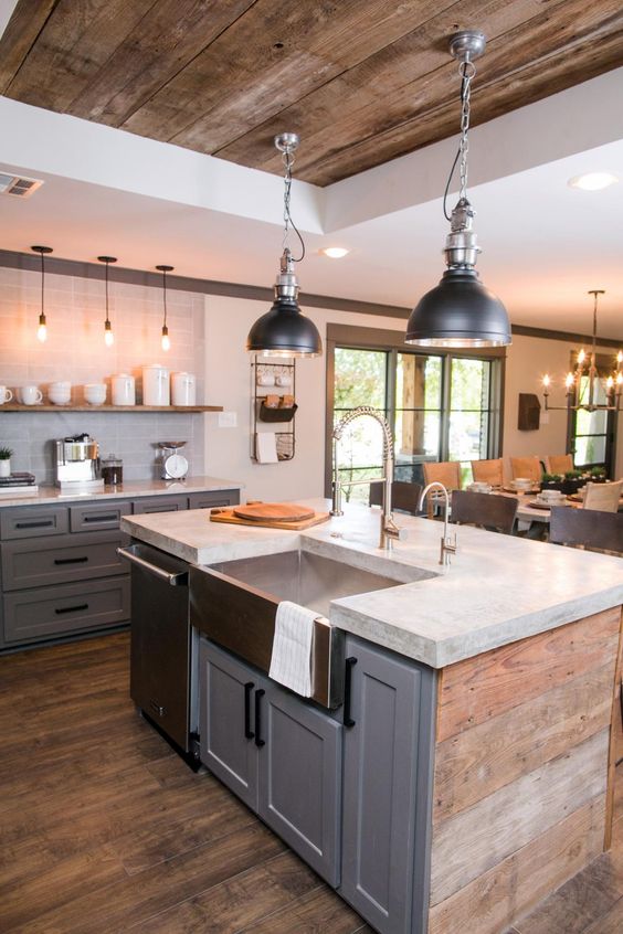 A rustic industrial kitchen in gray with a long shelf instead of upper cabinets, concrete countertops and metal hanging lamps