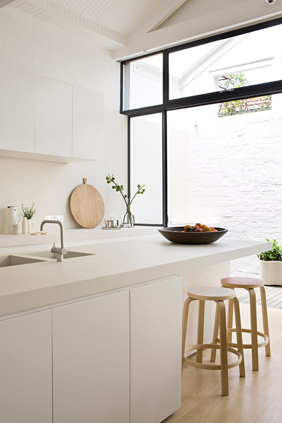 A serene white kitchen with sleek cabinets, a white tile backsplash, and white concrete countertops is amazing
