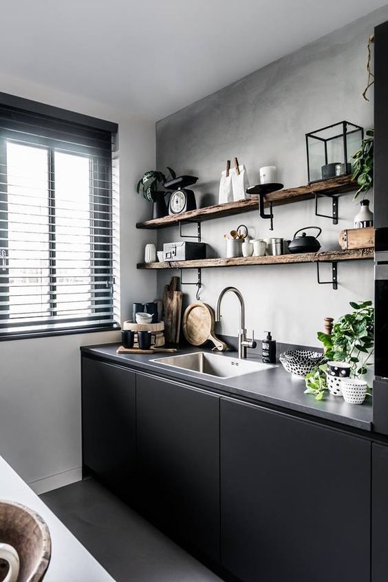 A small, sleek black kitchen with a concrete countertop, open shelves on the wall, and black accents for drama