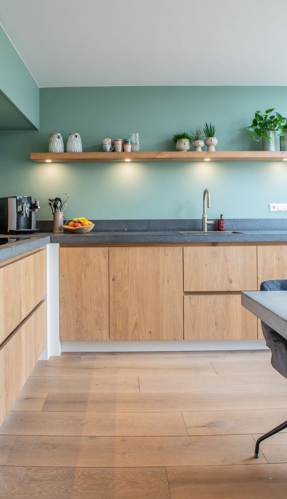 a stylish, modern kitchen with bright stained cabinets, green walls and a concrete countertop, as well as a floating shelf with lights