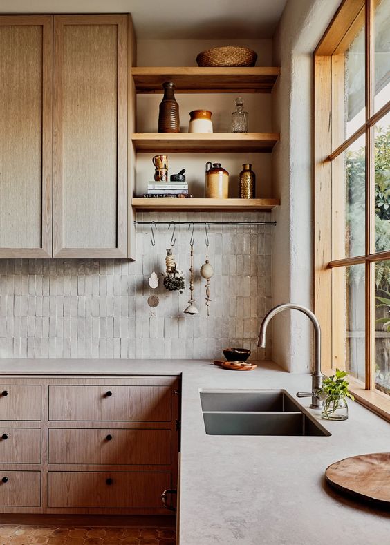 an inviting kitchen with wooden cabinets, concrete countertops and a thin tile backsplash and open shelving