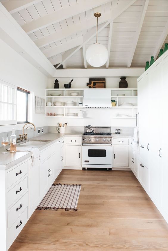 A white beach cottage kitchen with concrete worktop and backsplash and black handles for a chic look