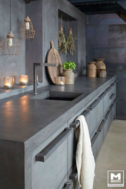 an industrial kitchen made entirely of concrete with stainless steel appliances and fittings as well as hanging lamps