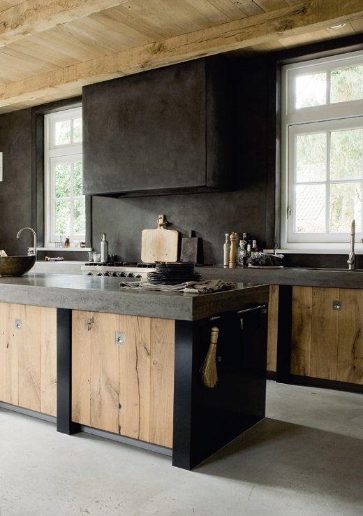 An industrial kitchen with elegant wooden cabinets, dark concrete countertops, a splashback and an extractor hood is a bold idea