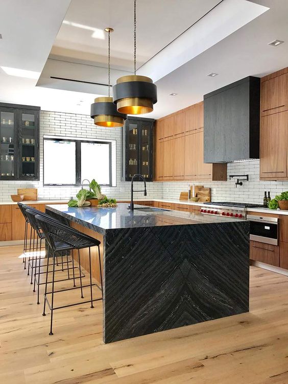A large black stained kitchen with a white subway tile backsplash and kitchen island with a black waterfall countertop to inspire