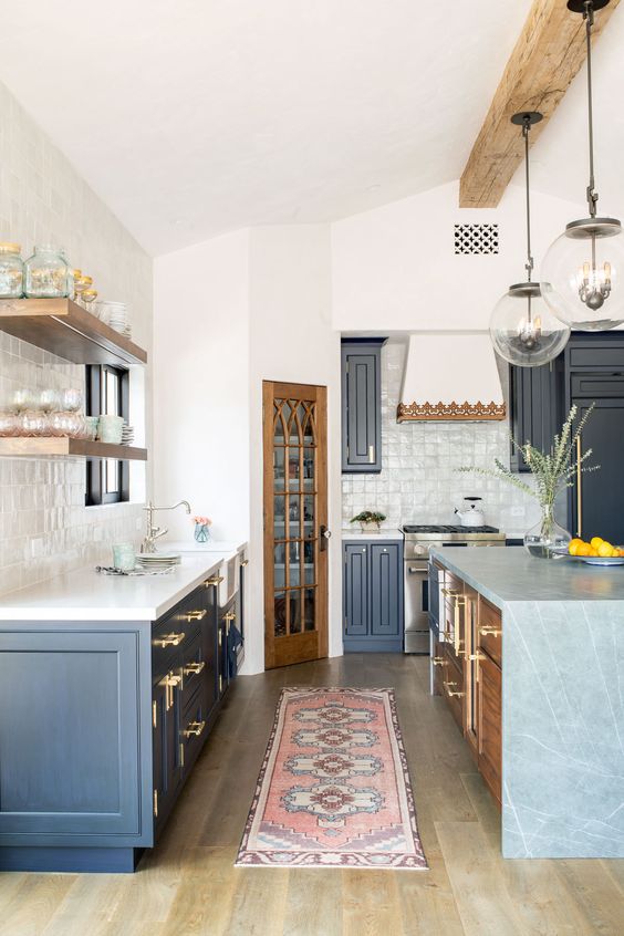 A navy farmhouse kitchen with white countertops, a stained kitchen island with a gray stone waterfall countertop is cozy