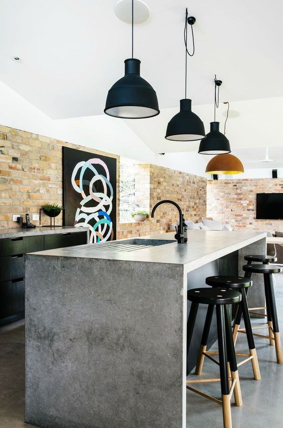 a great black kitchen with concrete countertops and a kitchen island with a concrete waterfall countertop and chic retro lamps