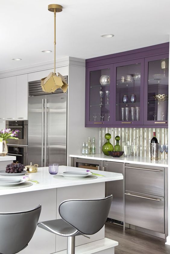 a striking silver and purple kitchen, a white kitchen island, gray stools, a faceted pendant lamp and a glossy kitchen backsplash
