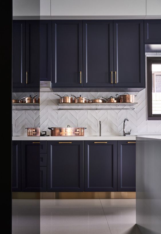 a vintage-style dark purple kitchen, white tile backsplash and countertops, and brass and copper accents