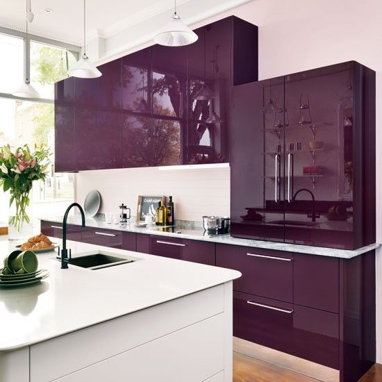 A glossy plum colored modern kitchen with white worktop and backsplash, a white kitchen island and hanging lamps