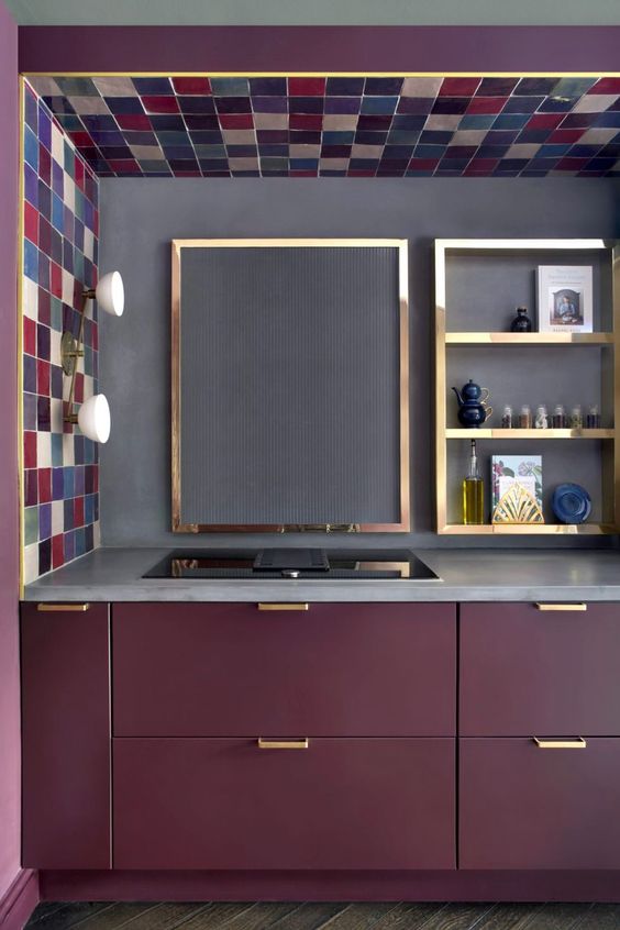 A beautiful matt purple kitchen with a concrete worktop and backsplash as well as gold frames and gold handles