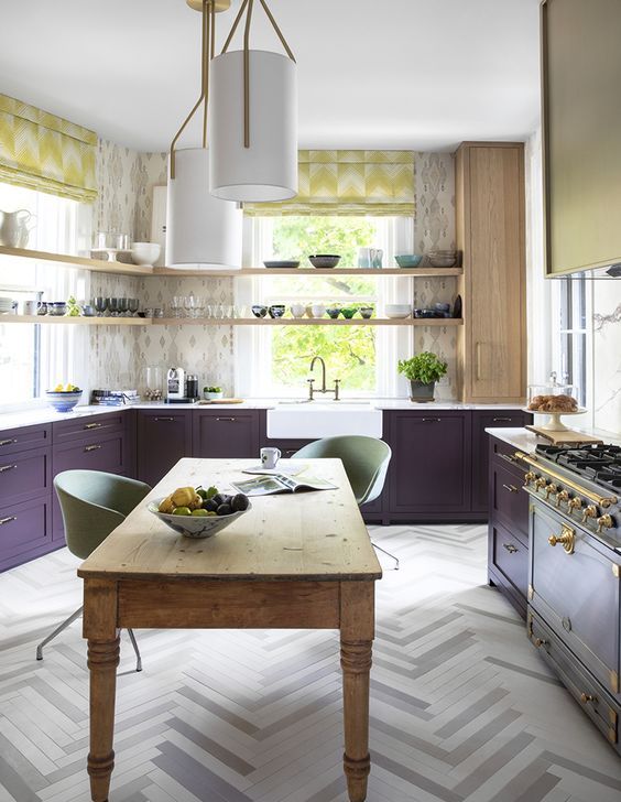 a stylish kitchen with dark purple cabinets, open shelving, a vintage stove and eye-catching textiles, and a vintage wooden table