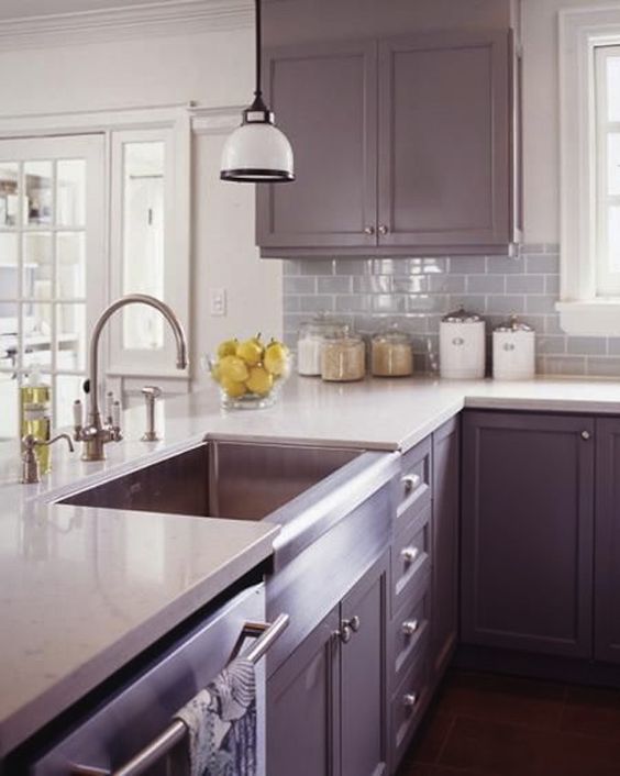 A vintage purple kitchen with white countertops, a gray subway tile backsplash, and a pendant lamp