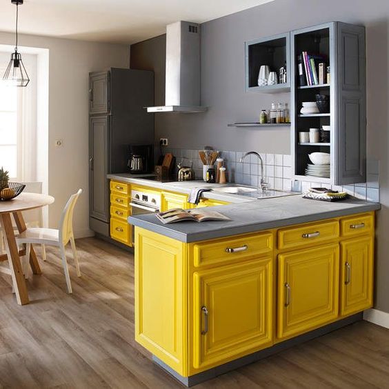 a bright kitchen with bright yellow base cabinets and gray upper cabinets, a white tiled back wall and stainless steel appliances