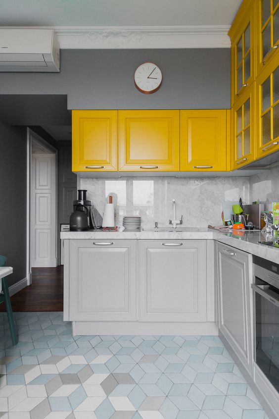 a bright, modern kitchen with gray and yellow cabinets, gray marble countertops and a backsplash, and stainless steel appliances