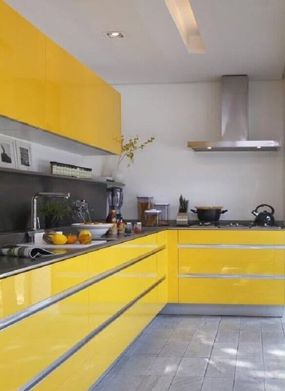 a bright yellow kitchen with gray backsplash and countertops, stainless steel appliances and some bold flowers