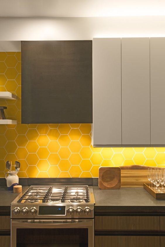 a minimalist kitchen with gray, dove gray and wood cabinets, a yellow hexagon tile backsplash and concrete countertops
