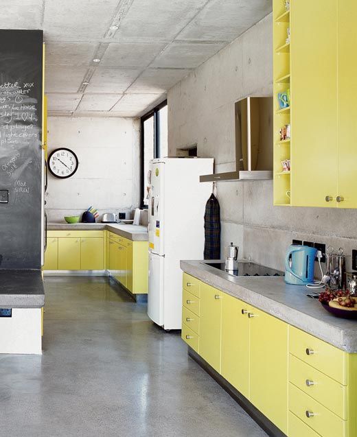A minimalist light yellow kitchen with concrete countertops and walls is a simple and bright space that has a contrasting effect