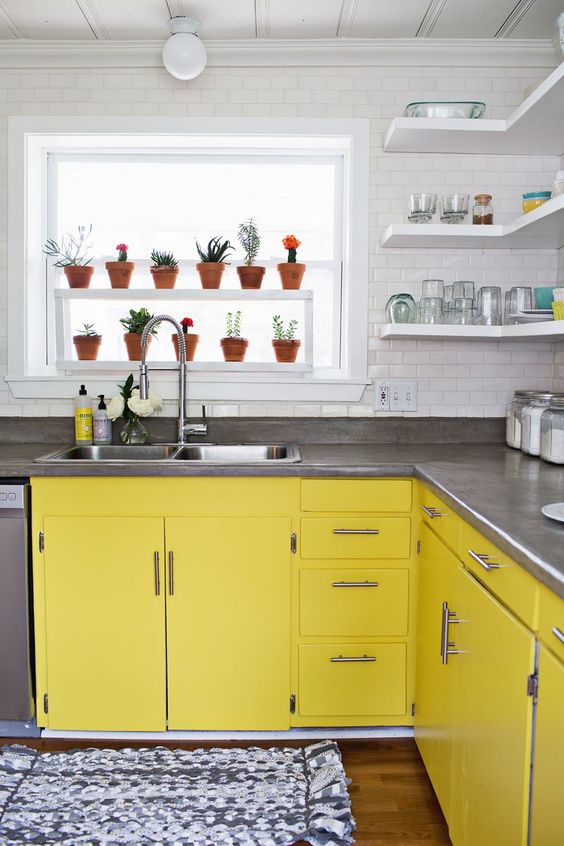 a white kitchen with bright yellow cabinets, gray stone countertops, and a white subway tile backsplash