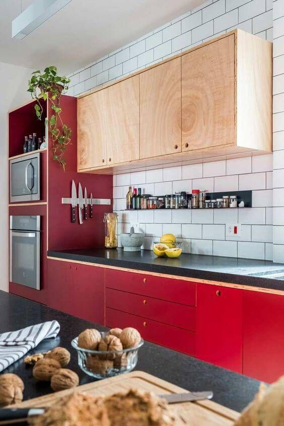 A bold mid-century modern kitchen with bright red base cabinets and neutral upper cabinets, plus a white tile backsplash